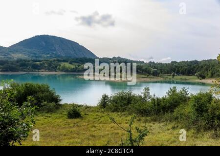 See Castel San Vincenzo, Damm, mit viel Vegetation und felsigen Berg im Hintergrund Stockfoto