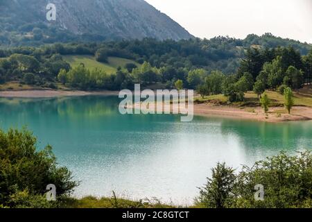 See Castel San Vincenzo, Damm, mit viel Vegetation und felsigen Berg im Hintergrund Stockfoto