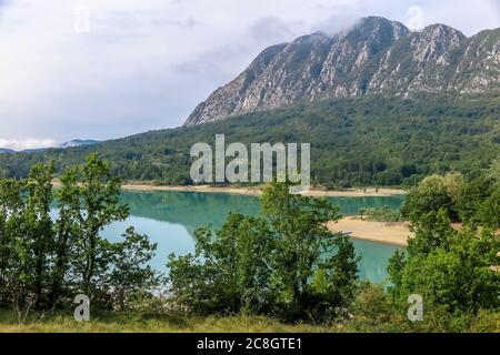 See Castel San Vincenzo, Damm, mit viel Vegetation und felsigen Berg im Hintergrund Stockfoto