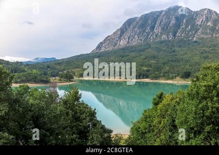 See Castel San Vincenzo, Damm, mit viel Vegetation und felsigen Berg im Hintergrund Stockfoto