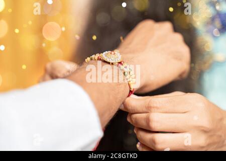 Nahaufnahme der Hände, Schwester, die Rakhi bindet, Raksha bandhan an das Handgelenk des Bruders während des Festivals oder der Zeremonie - Rakshanandhan feierte in ganz Indien als Stockfoto