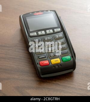 POS-Terminal isoliert auf Holzhintergrund, Nahaufnahme.Terminal-Kassenautomat für kontaktloses Bezahlen mit Kreditkarte. Bankausrüstung, N Stockfoto