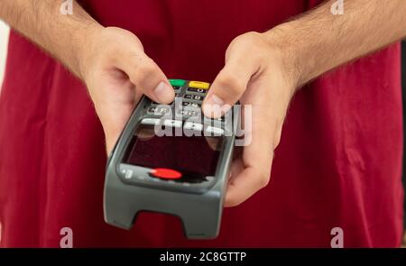 Mann hält eine Zahlung Swipe Maschine und Eingabe, Nahaufnahme. Kreditkartenleser, Kassenterminal-Bezahlkonzept. Stockfoto