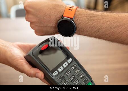 Mobile Bezahlung, Smart Watch nfc, drahtlose Nahfeldkommunikation. Kassierer und Kunden Hände mit POS-Maschine und Smart Watch, closeup vi Stockfoto