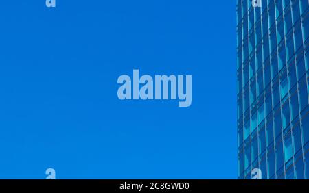 Blick auf die typische Glaswand-Fassade eines modernen Bürohochhauses. Blauer Himmel. Stockfoto