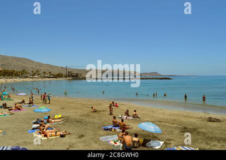 Touristen am Strand genießen die Sonne am Strand Playa De Las Americas Stockfoto