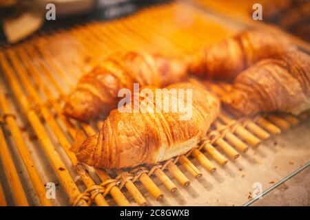 Croissants in der Vitrine der Bäckerei. Nahaufnahme von schönen appetitlichen goldenen Croissants im Café am Schaufenster. Auswahl an leckeren und buttrigen Stockfoto
