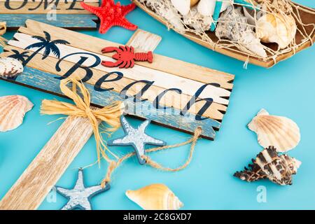 Holzschilder begrüßen Strand und Muscheln auf blauem Hintergrund. Stockfoto