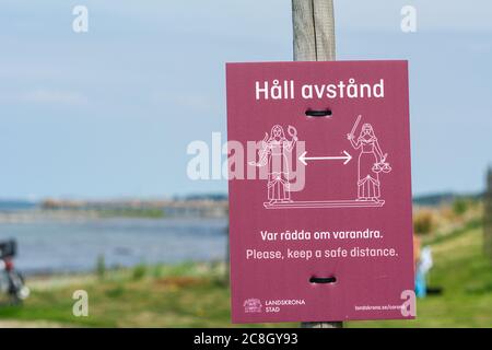 Landskrona, Schweden - 19. Juli 2020: Bild vom Borstahusener Strand und ein Schild mit der Erinnerung an die sichere Entfernung. Viele Menschen gehen während der Coronavirus-Pandemie zum Strand Stockfoto