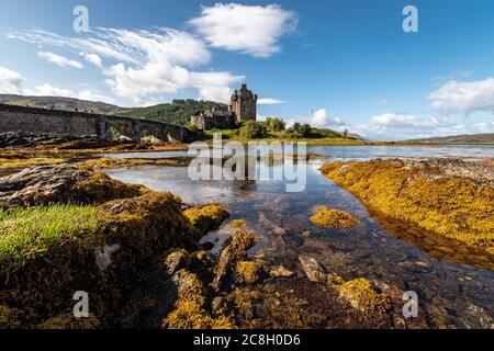 Dornie, SCHOTTLAND: Sommertage mit blauem Himmel über dem schönen schottischen Schloss Eilean Donan inmitten eines Sees. Stockfoto