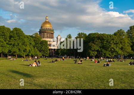 Sankt Petersburg, Russland - 3. Juni 2020 Rasen auf dem Senatsplatz mit Menschen, die vor der Isaakskathedrale ruhen. Stockfoto