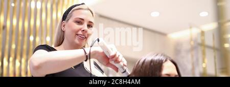 Haarschneider macht Locken für Frau Stockfoto