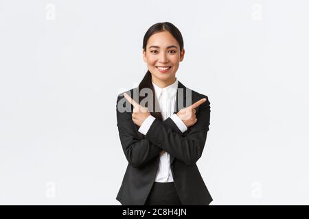 Gut aussehende asiatische Verkäuferin schlagen zwei Möglichkeiten vor. Attraktive Geschäftsfrau in schwarzem Anzug zeigt Finger seitlich, haben nur wenige Varianten, helfen zu machen Stockfoto