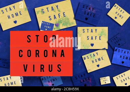 TOP CORONA VIRUS, ZU HAUSE bleiben und SICHER in Leuchtkasten auf blauem Hintergrund geschrieben. Gesundheitswesen und medizinisches Konzept. Draufsicht. Quarantänekonzept. Colla Stockfoto