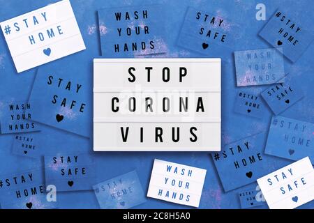 STOPPEN SIE CORONA VIRUS, ZU HAUSE bleiben, SICHER bleiben und WASCHEN SIE IHRE HÄNDE in Leuchtkasten auf blauem Hintergrund geschrieben. Gesundheitswesen und medizinisches Konzept. Draufsicht. Quarant Stockfoto