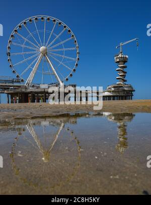 Der Bungee-Turm und das Rad auf Scheveningen Pier spiegelt sich in einem Teich am Strand Stockfoto