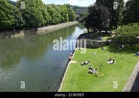 Touristen und Einheimische sonnen sich in den Bath Parade Gardens in Bath, Somerset Stockfoto