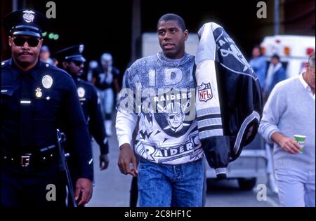 Magic Johnson of the Lakers Ankunft am Los Angeles Coliseum in Raiders Ausrüstung gekleidet, um einen L.A. zu beobachten Raiders NFL Fußballspiel im Jahr 1991. Stockfoto