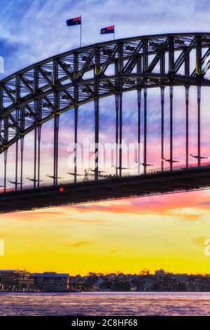 Ein Stahlbogen der Hafenbrücke von Sydney bei Sonnenuntergang vor dem strahlenden, bunten Himmel. Stockfoto