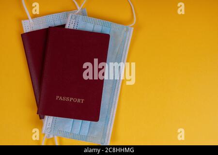 Pässe mit Masken auf gelbem Hintergrund. Konzept Urlaub oder Geschäftsreise während einer Pandemie. Stockfoto