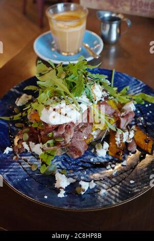 Holzfeuer gesundes Frühstück Kombination aus geräucherter Ente, gerösteten Kürbis auf Knoblauch Brioche mit wunderschönen pochierten Eiern und bestreuten Feta-Käse gekrönt Stockfoto