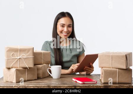 Kleinunternehmer, Startup und E-Commerce Konzept. Lächelnd asiatische Geschäftsfrau arbeiten von zu Hause aus, Verpackung verkaufte Artikel, Verpackung Boxen mit Bestellungen für Stockfoto