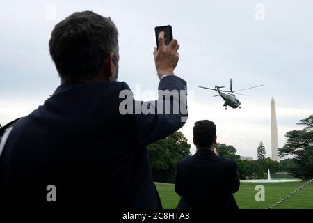 Washington, DC, USA. Juli 2020. Ein Reporter hält sein Telefon hoch, als Marine One, der US-Präsident Donald J. Trump trägt, am Freitag, den 24. Juli 2020, vom South Lawn des Weißen Hauses in Washington, DC, USA, abhebt. US-Präsident Donald Trump kündigte heute neue Politik an, die darauf abzielt, die Preise für verschreibungspflichtige Medikamente unter Medicare zu senken, indem sie sie mit den in anderen Ländern bezahlten Preisen verknüpfen und es Amerikanern ermöglicht, verschreibungspflichtige Medikamente aus Kanada zu kaufen.Quelle: Stefani Reynolds/Pool via CNP Stockfoto