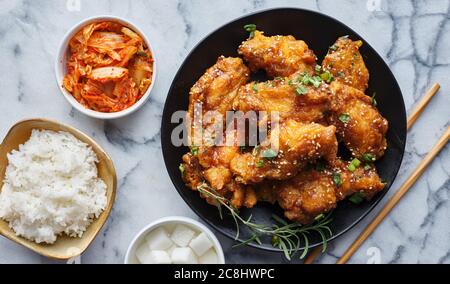 Knusprig gebratene koreanische Hähnchenflügel in galbi-Sauce mit eingelegtem Rettich, Kimchi und Reisbeilagen Stockfoto