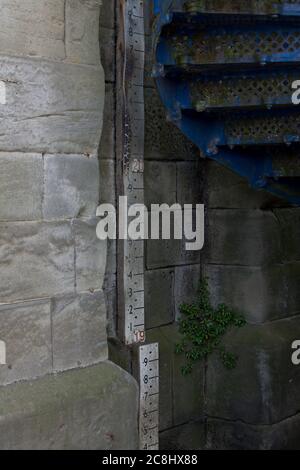 Hochwassersäule entlang eines Flusses, unter einer Brücke, in einem Dorf, Hochwasser, Wetter, Hochwasseranzeige, Hochwasserlineal, Aufzeichnungen, Hochwasserwarnmeldungen, Vorbereitung Stockfoto