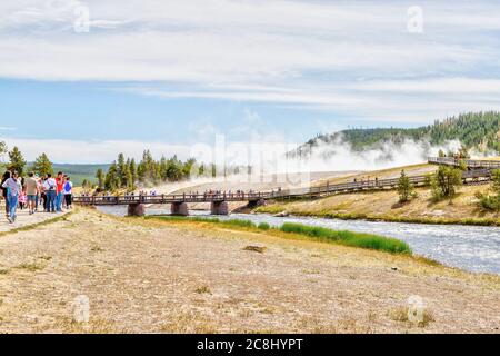 Wyoming, USA - 24. August 2019: Besucher nähern sich der Fußgängerbrücke zur Grand Prismatic Spring im Yellowstone National Park, während Dampf aus der Therme steigt Stockfoto