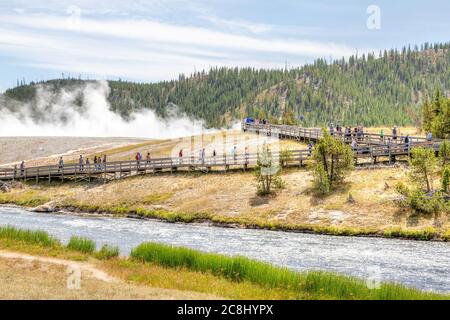 Wyoming, USA - 24. August 2019: Besucher nähern sich der Fußgängerbrücke zur Grand Prismatic Spring im Yellowstone National Park, während Dampf aus der Therme steigt Stockfoto