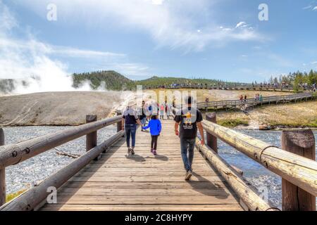 Wyoming, USA - 24. August 2019: Besucher nähern sich der Fußgängerbrücke zur Grand Prismatic Spring im Yellowstone National Park, während Dampf aus der Therme steigt Stockfoto