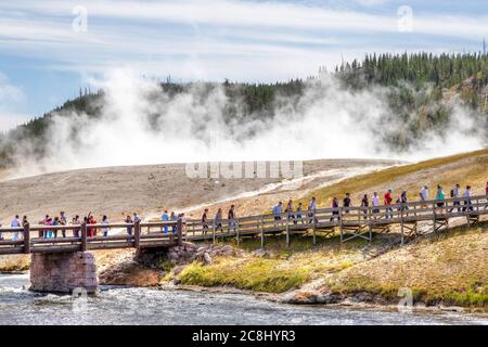 Wyoming, USA - 24. August 2019: Besucher nähern sich der Fußgängerbrücke zur Grand Prismatic Spring im Yellowstone National Park, während Dampf aus der Therme steigt Stockfoto