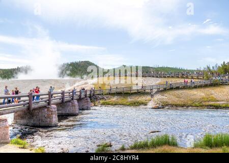 Wyoming, USA - 24. August 2019: Besucher nähern sich der Fußgängerbrücke zur Grand Prismatic Spring im Yellowstone National Park, während Dampf aus der Therme steigt Stockfoto