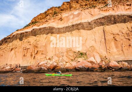 Eine Frau, die vor der Küste unter den Klippen von Isla Espirito Santo, Golf von Kalifornien, BCS, Mexiko, Kajak. Stockfoto