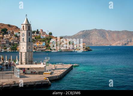 Der Uhrenturm und der Eingang zum Hafen von Symi, einer winzigen Insel der Dodekanes, in Griechenland. Stockfoto