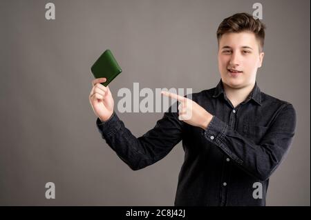 Portrait von ernst stilvolle attraktive Mann mit einem lässigen schwarzen Hemd zeigt Brieftasche isoliert auf grauem Hintergrund mit Kopie Raum Werbung ar gekleidet Stockfoto