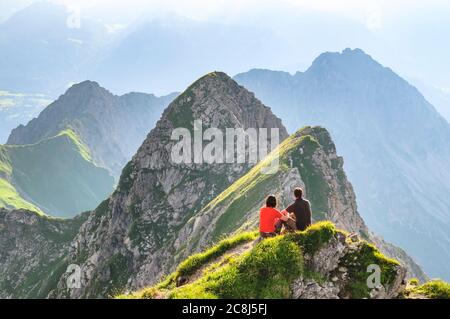 Wanderer sitzen in der Abendsonne auf dem Berggipfel bei Nebelhorn im bayerischen Allgäu Stockfoto