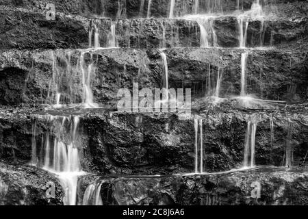 Wasser fällt in mehreren kleinen Kaskaden über Felsstufen, in einer langen Belichtung schwarz-weiß-Foto. Stockfoto