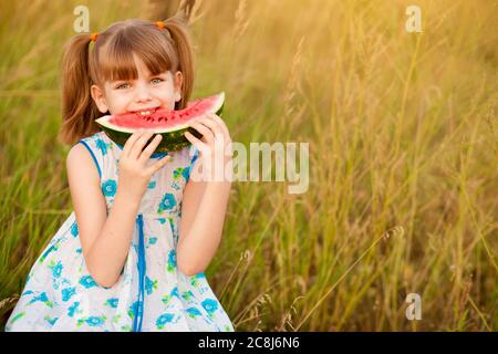 Happy niedlichen kleinen Mädchen essen Wassermelone auf Gras im Sommer Stockfoto