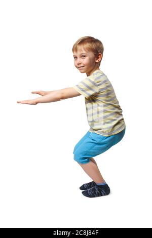 Junge in blauen Shorts und einem gelb gestreiften T-Shirt tun Kniebeugen Stockfoto