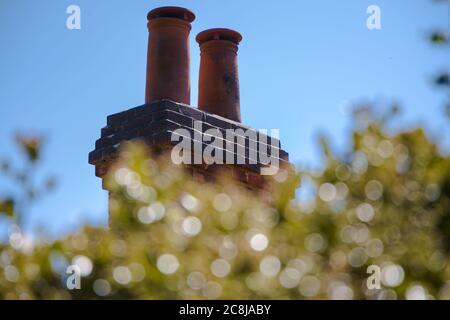 Schornstein spässt hinter die Blätter, gegen den blauen Himmel Stockfoto