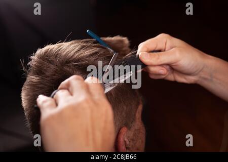 Männer Haarschnitt. Friseurwerkzeuge. Haarschnitt mit Schere Temporal Lappen Nahaufnahme. Stockfoto