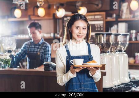 Asian Coffee Shop Besitzer Serving Backwaren Kuchen und Kaffeetasse an Kunden in Coffee Shop, Kleinunternehmen Eigentümer und Startup in Coffee Shop und Restaurant, Stockfoto