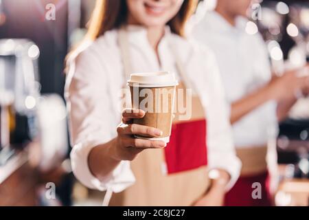 Asian Barista serviert eine Papiertasse Kaffee an Kunden in Coffee Shop, Kleinunternehmen Eigentümer und Startup in Coffee Shop und Restaurant Konzept Stockfoto