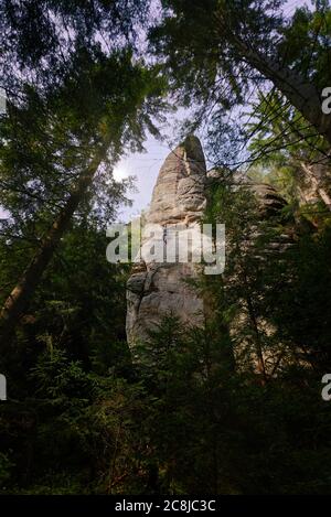 Berühmte Sandsteinfelsen Türme von Adrspach und Teplice Rocks. Eine Frau klettert auf einen überhängenden Felsen Stockfoto