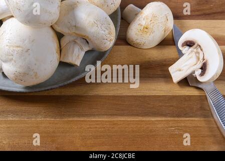 Frische Champignon-Pilze auf Holzschnittplatte. In Nahaufnahme geschnittener weißer Champignon. Stockfoto