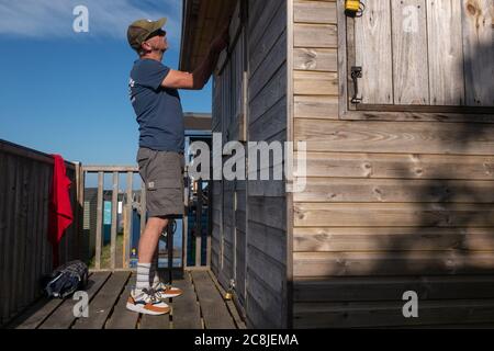Damit alle Türen und Schlösser gesichert sind, schließt ein Besucher am 18. Juli 2020 eine Strandhütte an der Strandpromenade in Whitstable, Kent, England. Stockfoto