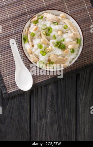 Ingwer-Huhn Jook Reis Haferbrei Nahaufnahme in einer Schüssel auf dem Tisch. Vertikale Draufsicht von oben Stockfoto