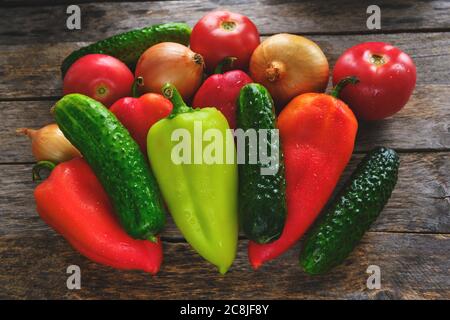 Paprika, Gurken, Zwiebeln und Tomaten auf altem Holzhintergrund Stockfoto